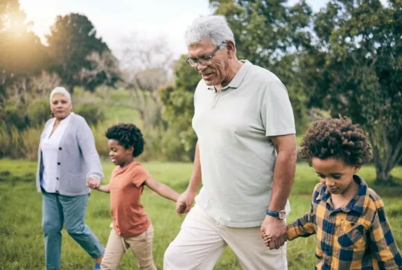 Park grandparents and children holding hands while walking as a family presents connection for grandparents raising grandchildren