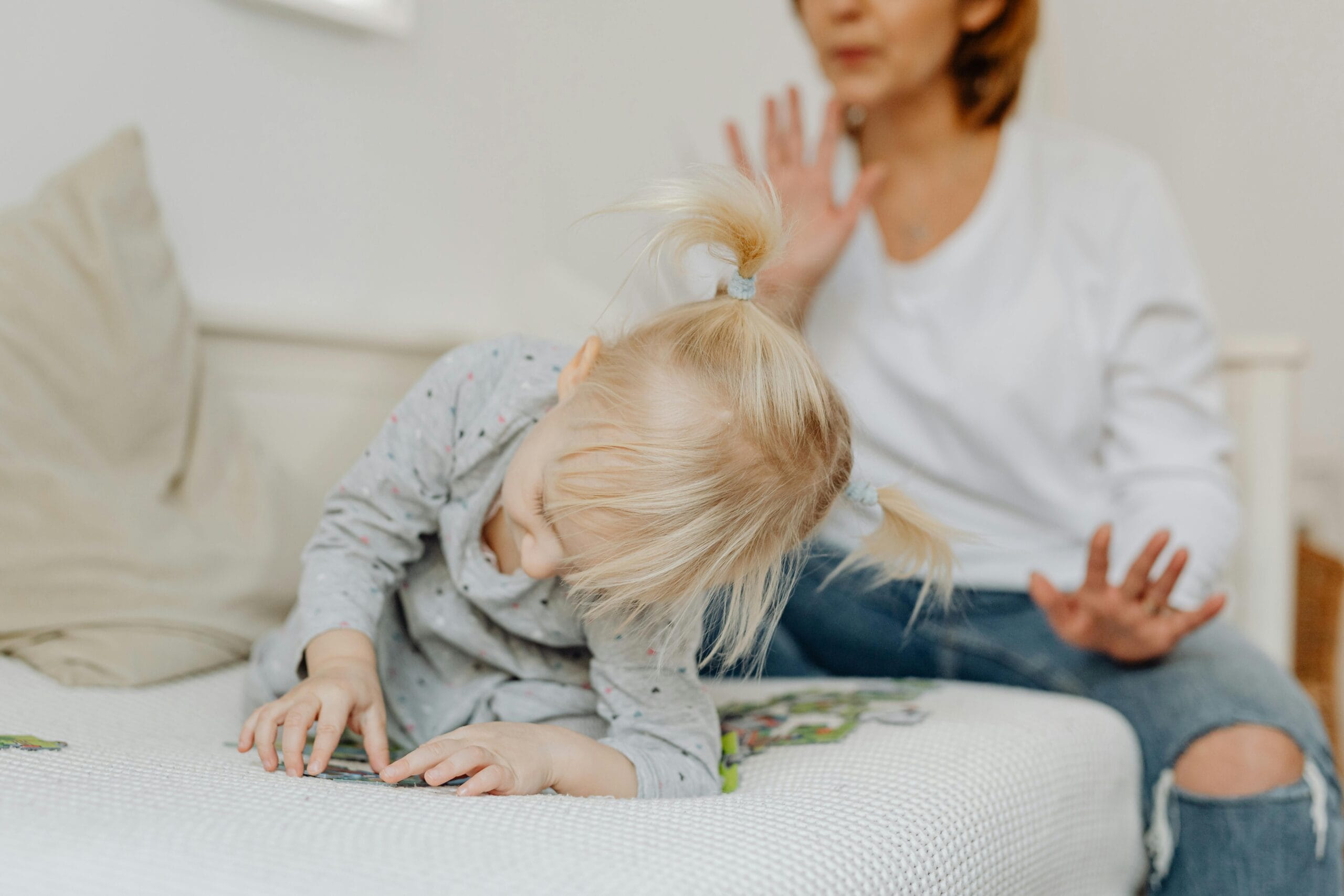 Woman on Couch and Daughter Playing with Puzzles women expressing 90-second rule for parents